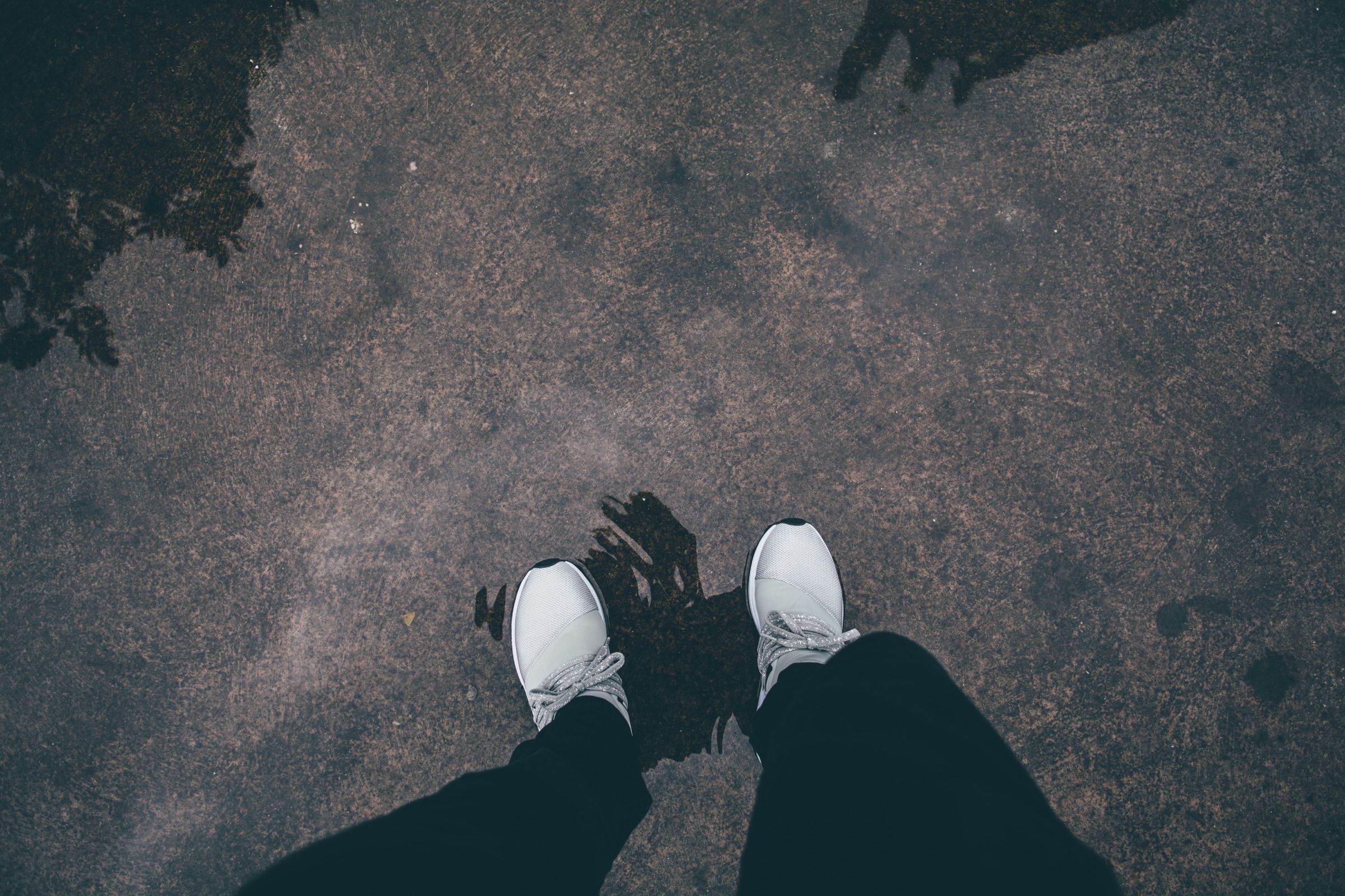Grey ARKK sneakers reflected in a puddle