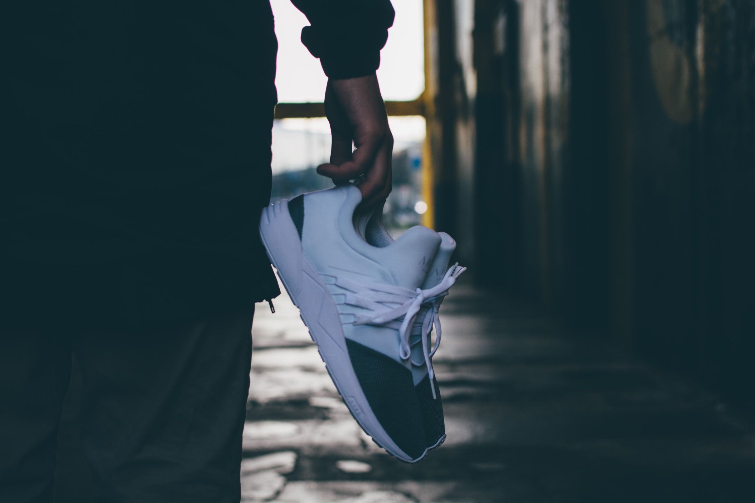 White ARKK sneaker held up in one hand