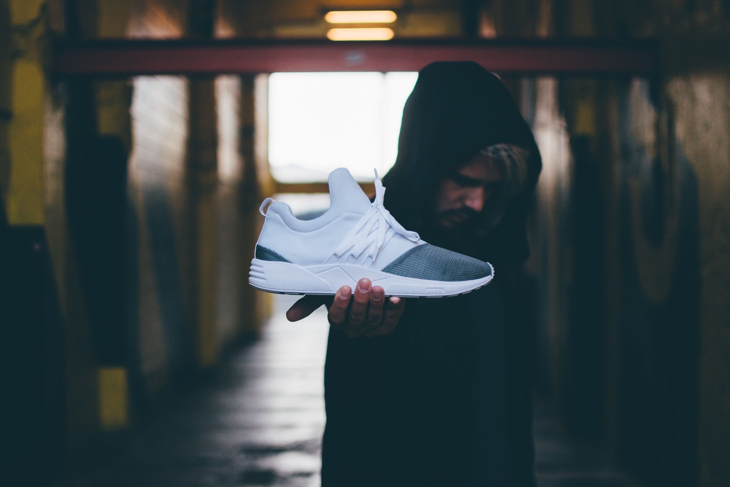 White ARKK sneakers held out on open hands