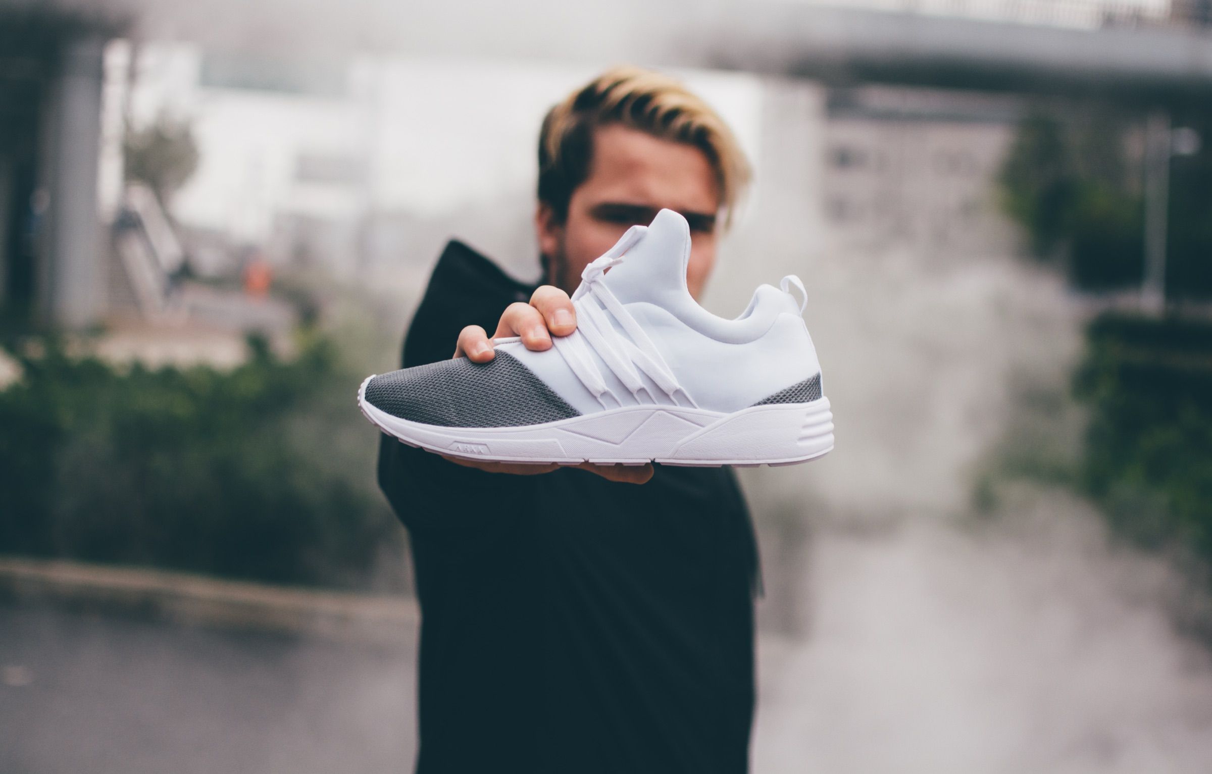 White ARKK sneakers held amid drifting smoke