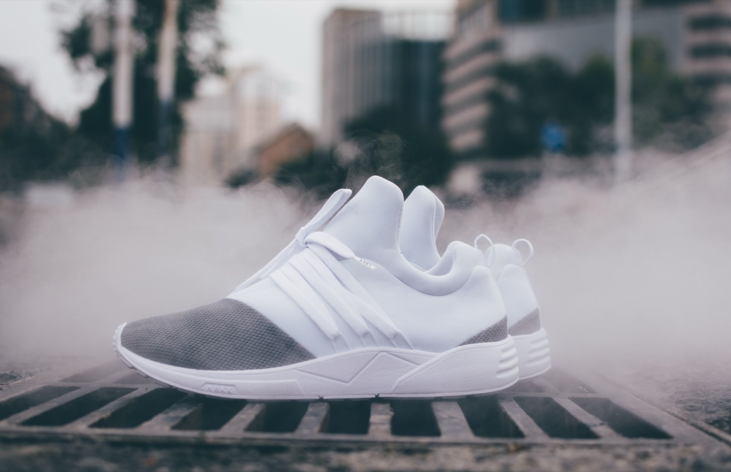 White ARKK sneakers on the ground amid drifting smoke