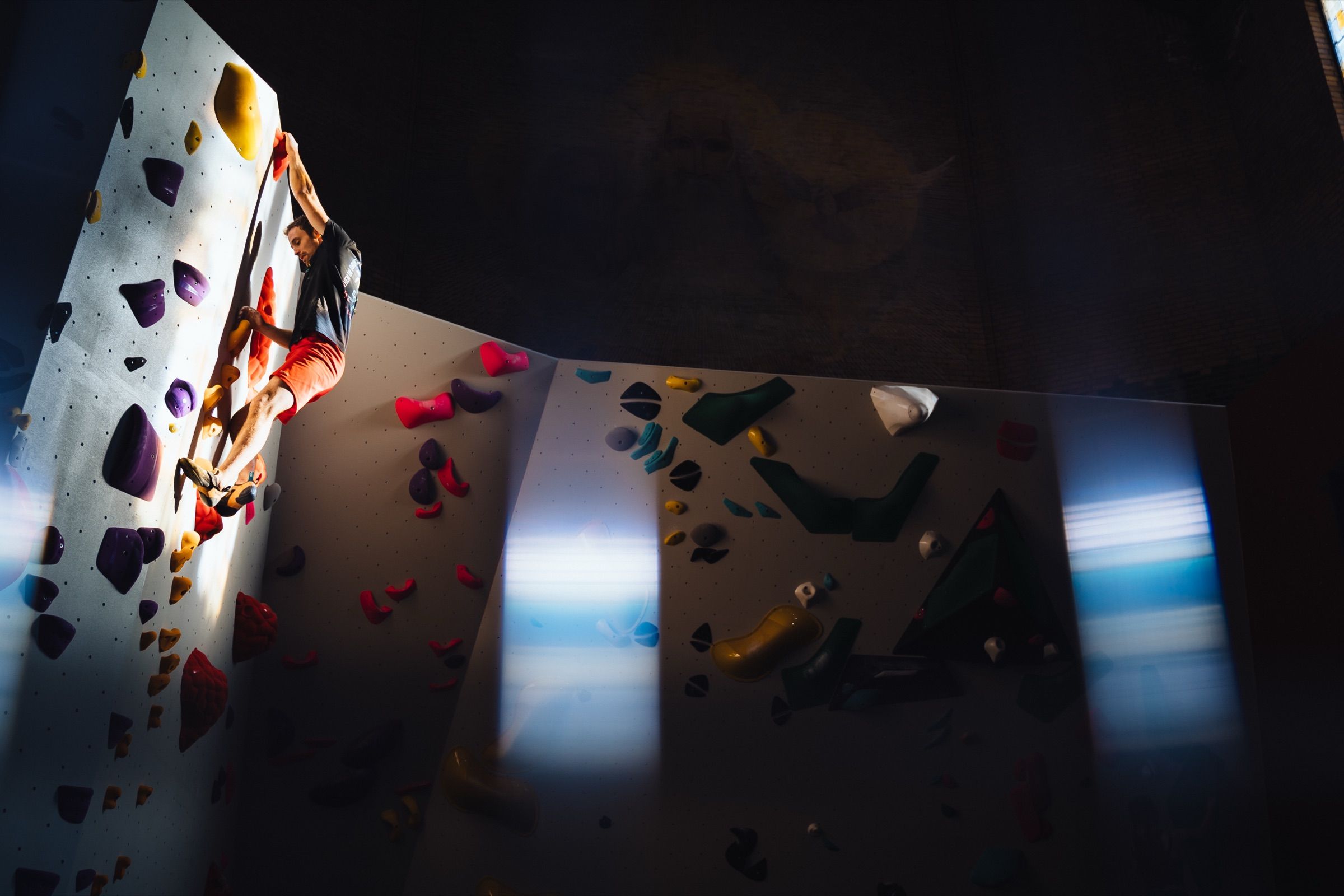 Man mid-move on a bouldering wall at Nirvana