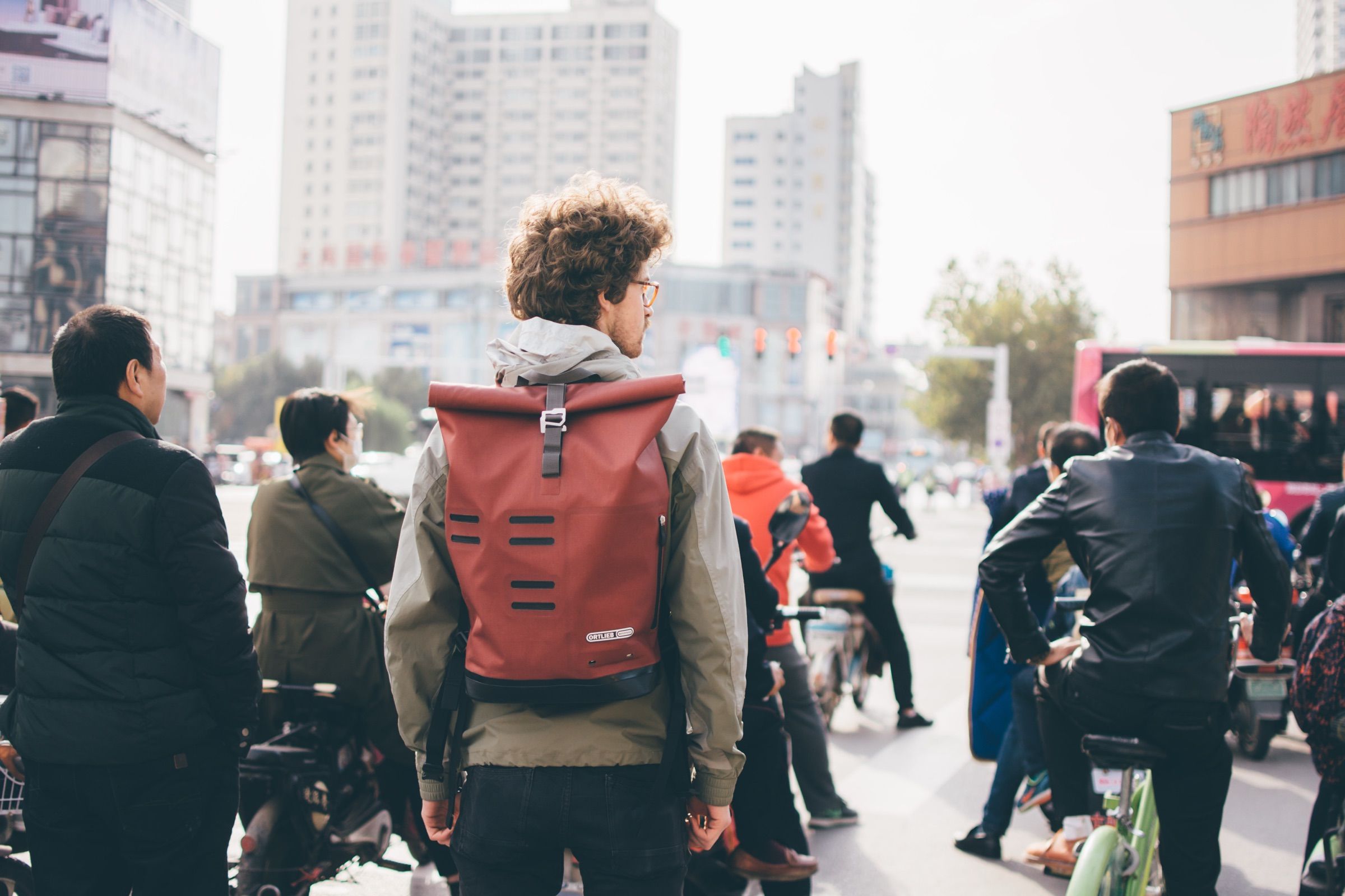 Traveler wearing an Ortlieb backpack crossing city traffic