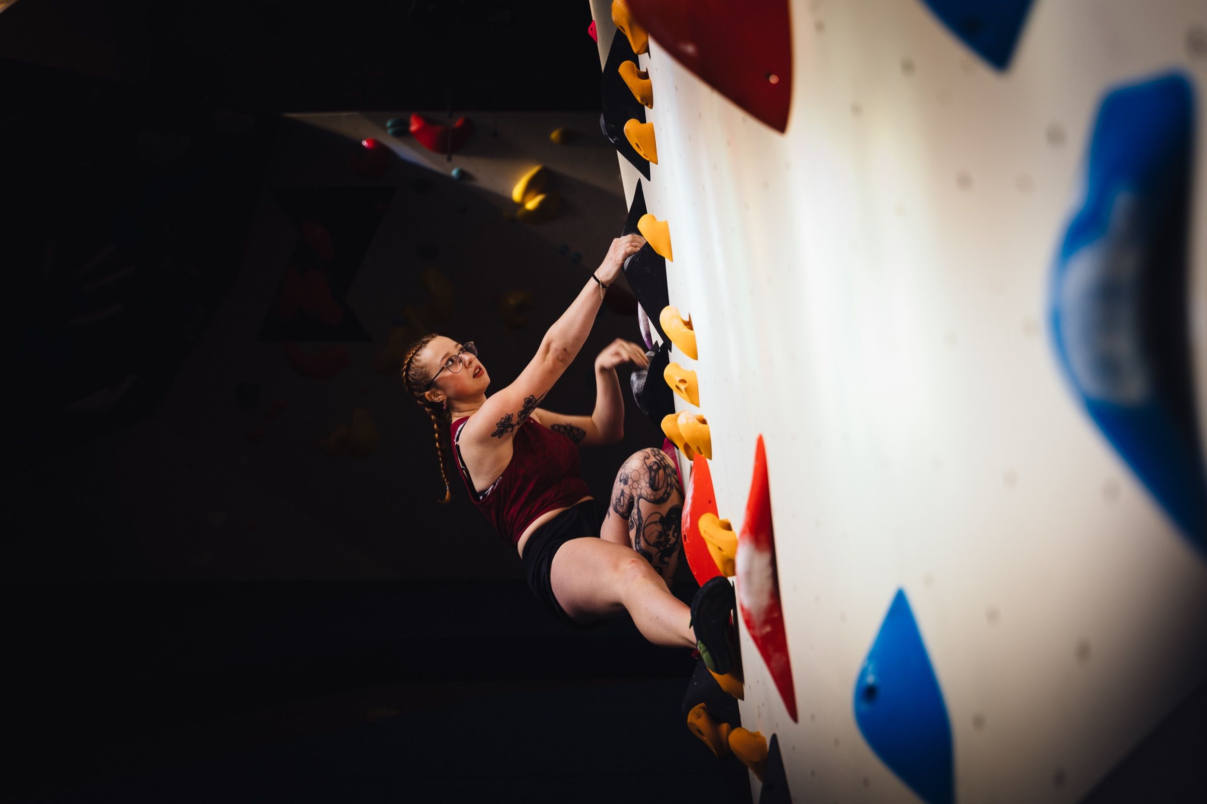 Tattooed climber working up a wall at Boulderhal Nirvana